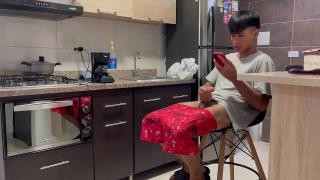 A boy is sitting in the kitchen masturbating