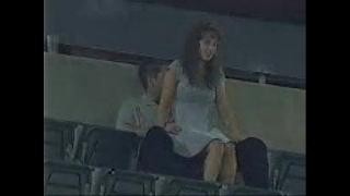 A couple is having sex in the stadium stands.