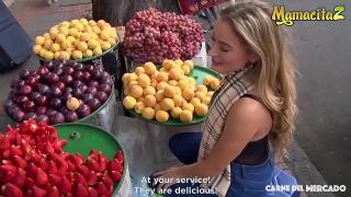 A blonde buys fruit on the street.